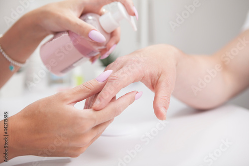 Close up of professional manicurist applying hand cream on male hands after manicure