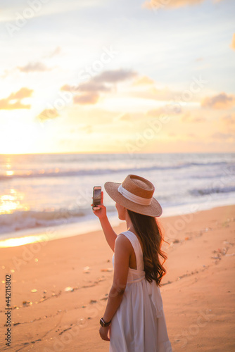 woman traveler enjoying for view of the beautiful sea on her holiday.beautiful Lady tourist taking photo and walking on the beach.