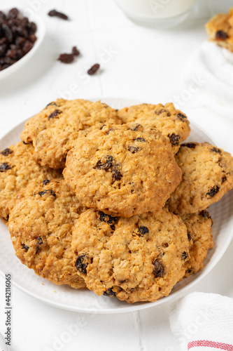 Homemade oatmeal cookies with raisins in a white plate on a light background closeup 