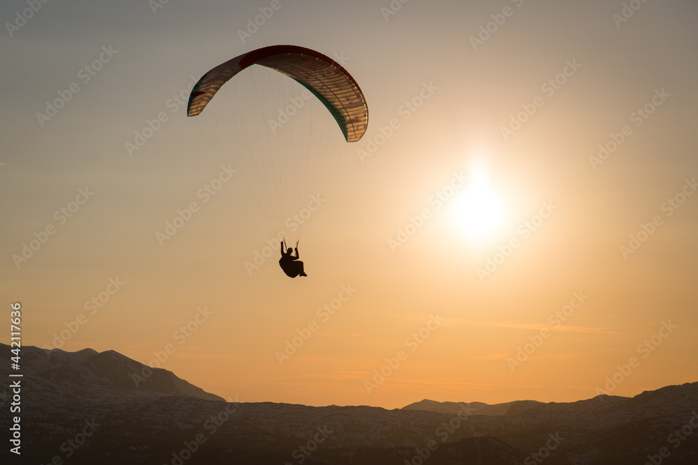 Paraglider flying in sunset over the mountains Paraglider flying in sunset over the mountains