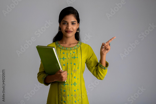 Pretty young girl posing with the book on grey background