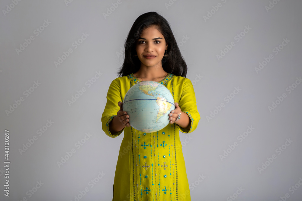 young girl holding the world globe and posing on a grey background. young girl holding the world globe and posing on a grey background.