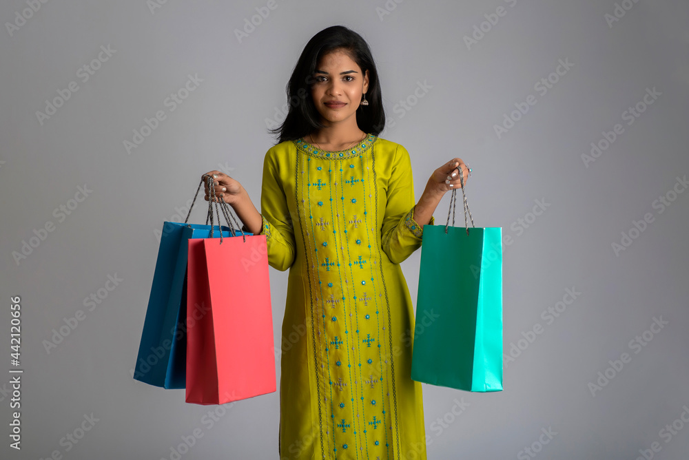 Beautiful young girl holding and posing with shopping bags on a grey background