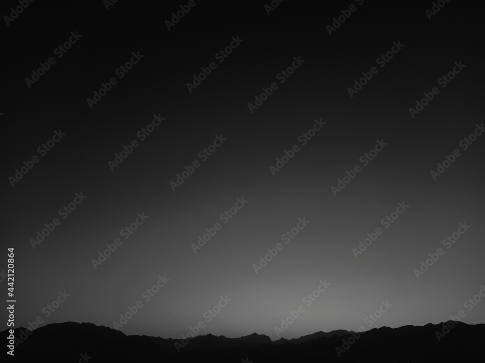 A beautiful black and white shot of mountain range peaks with a large view of the sky