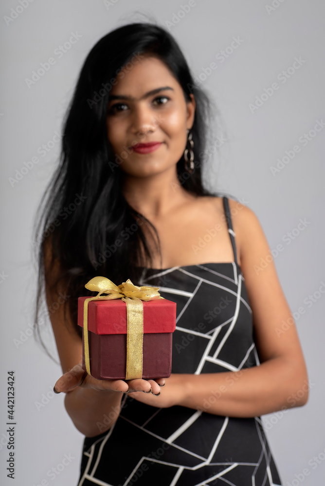 Portrait of a pretty young girl posing with gift box on grey background. Portrait of a pretty young girl posing with gift box on grey background.