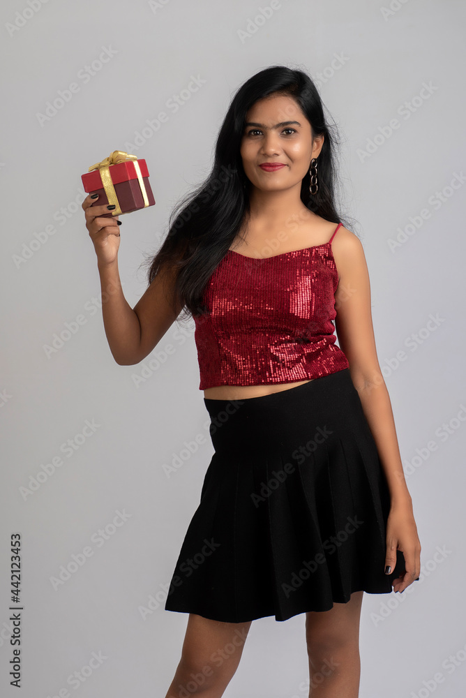 Portrait of a pretty young girl posing with gift box on grey background. Portrait of a pretty young girl posing with gift box on grey background.