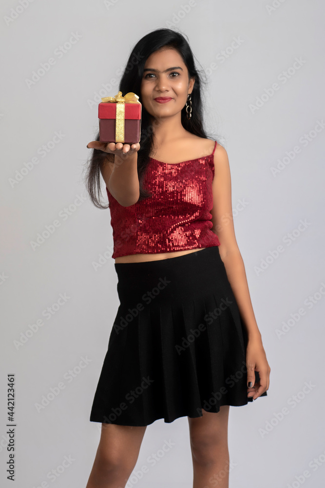 Portrait of a pretty young girl posing with gift box on grey background. Portrait of a pretty young girl posing with gift box on grey background.