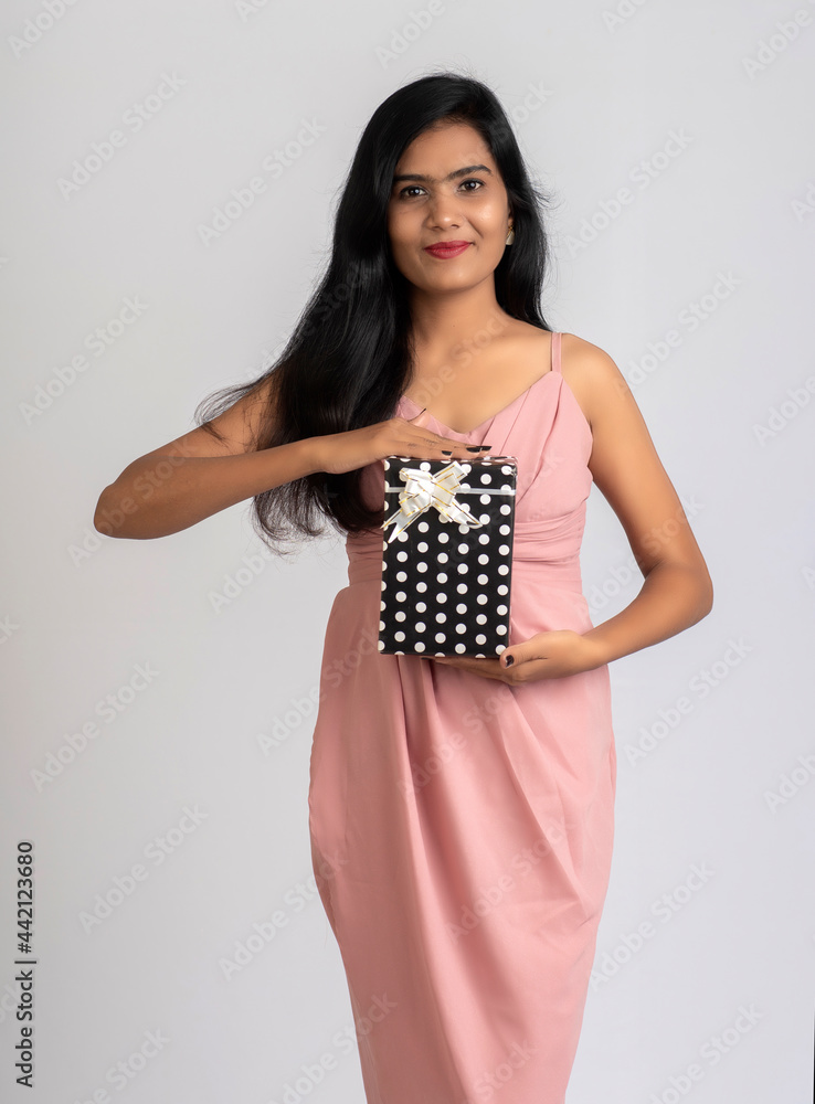 Portrait of a pretty young girl posing with gift box on grey background. Portrait of a pretty young girl posing with gift box on grey background.