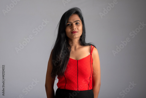 Young beautiful smiling girl in red and black outfit posing on grey background.