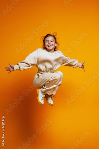 Happy little girl jumping on a yellow background. Space for text. children's sports concept.