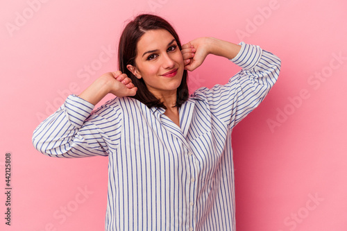 Young caucasian woman isolated on pink background stretching arms, relaxed position. © Asier
