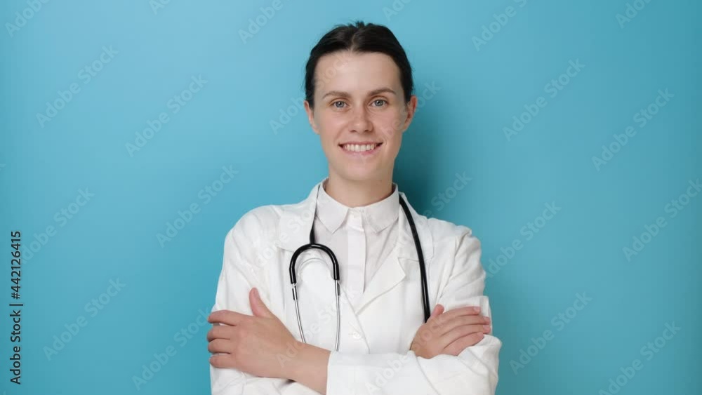 Confident smiling woman doctor wear white medical coat, stethoscope look at camera standing on blue studio background. Portrait of young female health care professional medical practitioner physician Confident smiling woman doctor wear white medical coat, stethoscope look at camera standing on blue studio background. Portrait of young female health care professional medical practitioner physician
