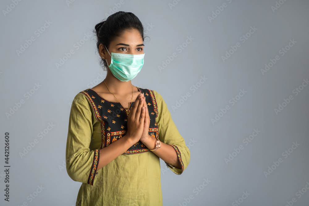 Portrait of a girl wearing a medical mask doing greeting with Namaste gesture. Portrait of a girl wearing a medical mask doing greeting with Namaste gesture.