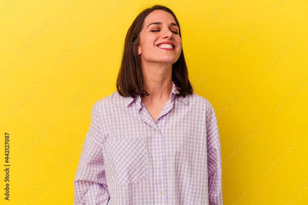 Young caucasian woman isolated on yellow background laughs and closes eyes, feels relaxed and happy. Young caucasian woman isolated on yellow background laughs and closes eyes, feels relaxed and happy.