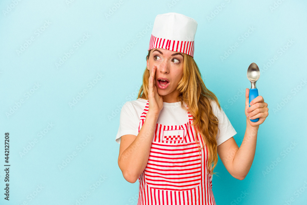 Caucasian ice cream maker woman holding an ice cream scoop isolated on blue background is saying a secret hot braking news and looking aside Caucasian ice cream maker woman holding an ice cream scoop isolated on blue background is saying a secret hot braking news and looking aside
