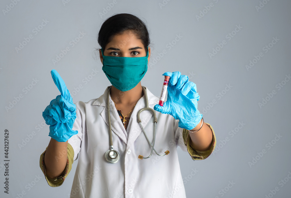 Woman Doctor showing signs with holding a test tube with blood sample for coronavirus or 2019-nCoV analyzing. Woman Doctor showing signs with holding a test tube with blood sample for coronavirus or 2019-nCoV analyzing.