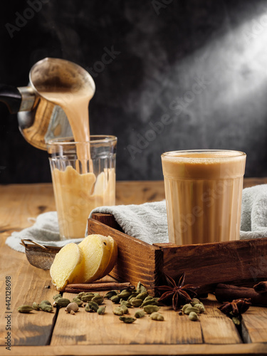 The traditional Indian drink masala chai is poured into a faceted glass glass. Copy space.