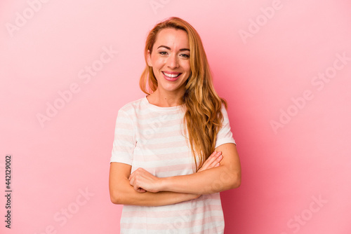 Caucasian blonde woman isolated on pink background who feels confident, crossing arms with determination.