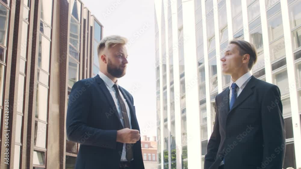 Confident businessman and his colleague in front of modern office building. Financial investors are talking outdoor. Banking and business. Confident businessman and his colleague in front of modern office building. Financial investors are talking outdoor. Banking and business.