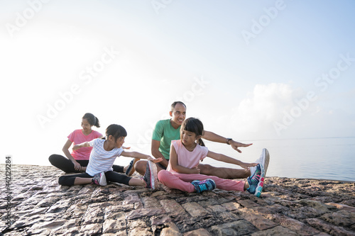 Fototapeta Naklejka Na Ścianę i Meble -  asian parent and children do sport outdoor. healthy family stretching and exercise in the morning