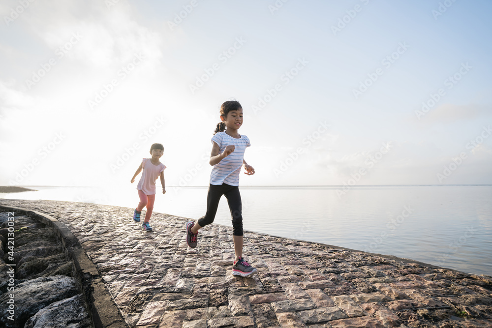 two Asian girl is jogging at the beach in the morning