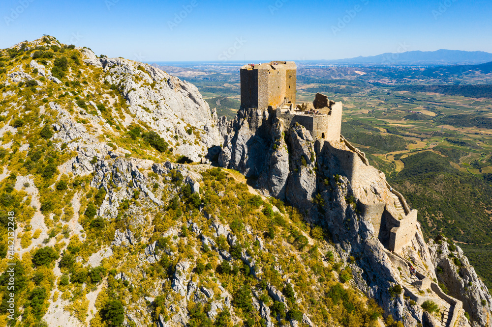 Aerial view of stone ruins of ancient fortified Chateau de Queribus on rocky hilltop on sunny summer day, Aude departement, France..