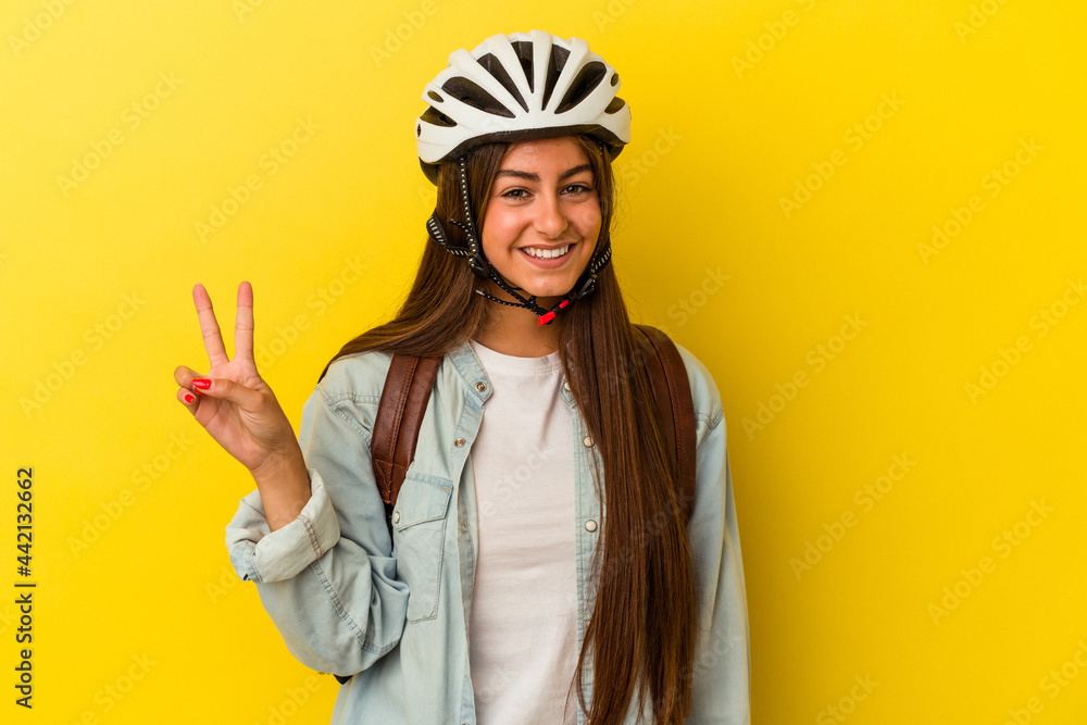 Young student caucasian woman wearing a bike helmet isolated on yellow background showing number two with fingers. Young student caucasian woman wearing a bike helmet isolated on yellow background showing number two with fingers.