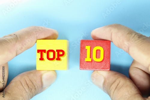 hand holding a wooden cube with the word Top 10