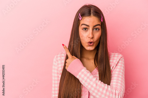 Young caucasian woman isolated on pink background pointing to the side