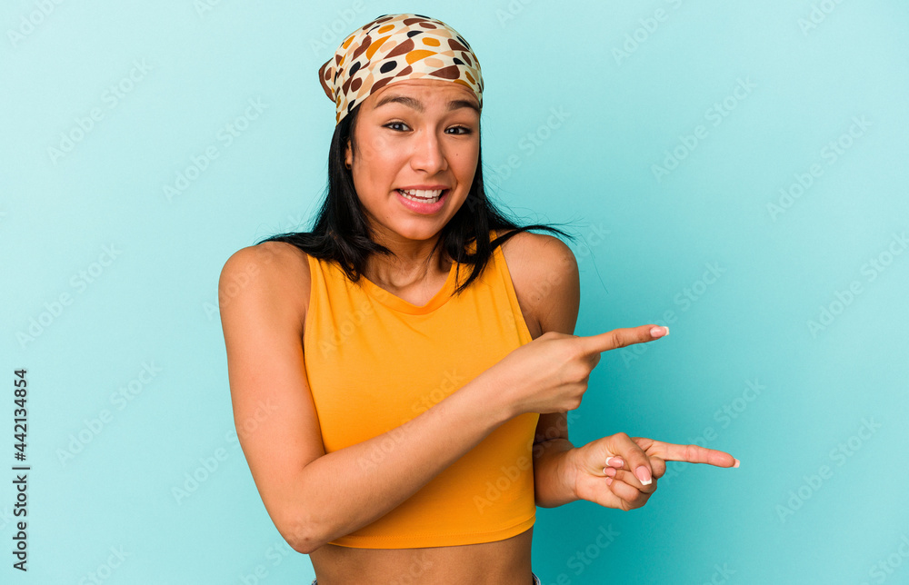 Young Venezuelan woman isolated on blue background shocked pointing with index fingers to a copy space.