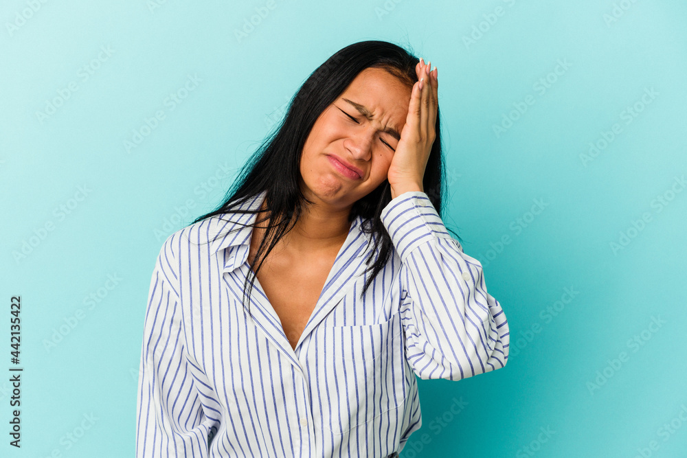 Young Venezuelan woman isolated on blue background tired and very sleepy keeping hand on head. Young Venezuelan woman isolated on blue background tired and very sleepy keeping hand on head.
