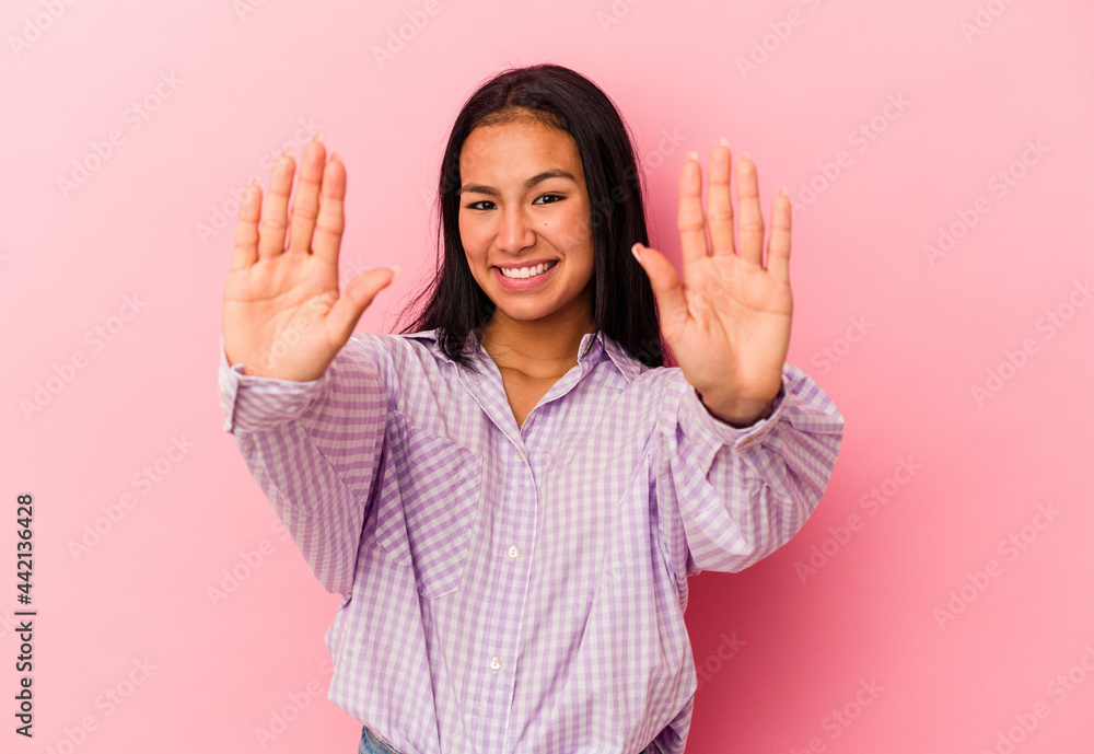 Young Venezuelan woman isolated on pink background showing number ten with hands. Young Venezuelan woman isolated on pink background showing number ten with hands.