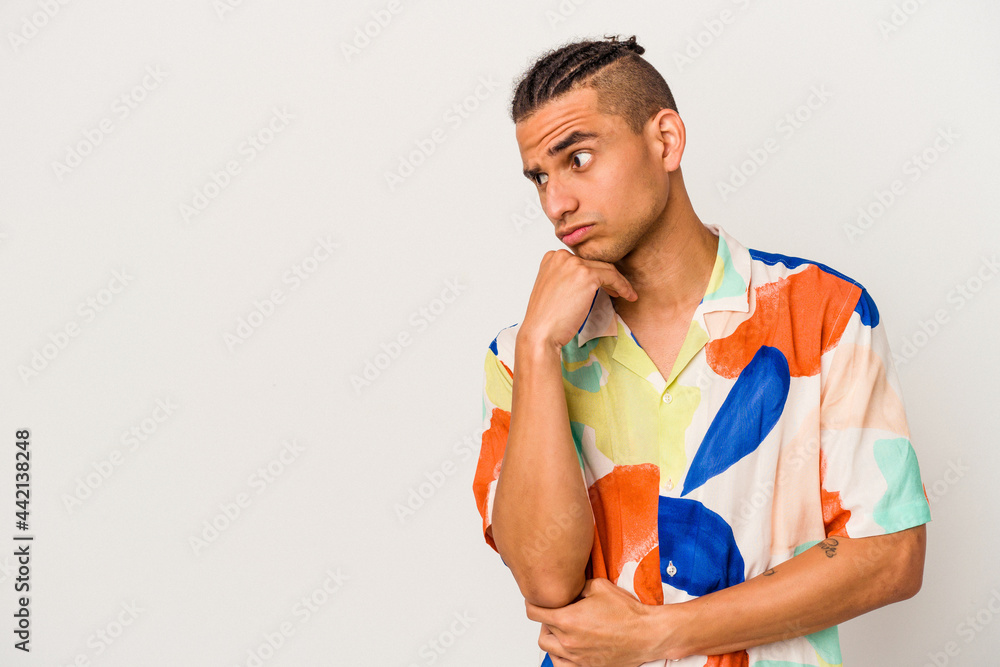 Young venezuelan man isolated on white background looking sideways with doubtful and skeptical expression. Young venezuelan man isolated on white background looking sideways with doubtful and skeptical expression.