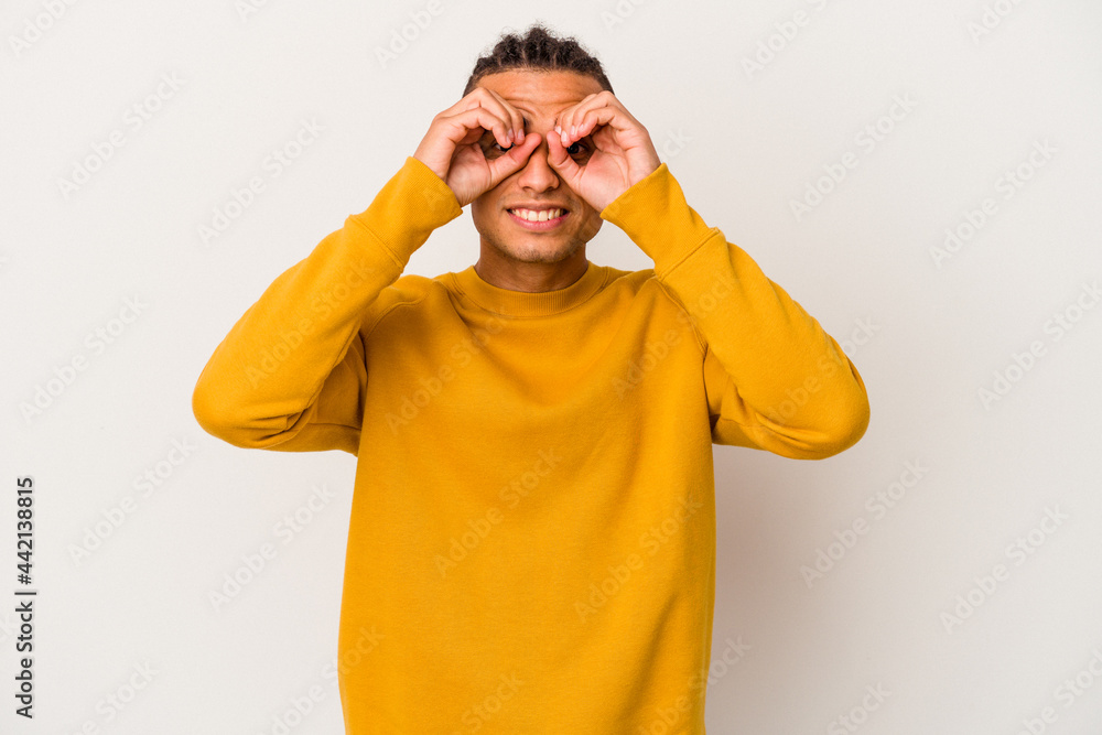 Young venezuelan man isolated on white background showing okay sign over eyes Young venezuelan man isolated on white background showing okay sign over eyes