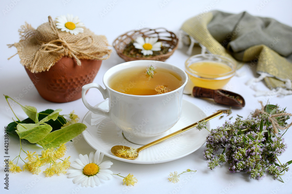 Composition on a white background. A cup of herbal tea, honey, linden flowers, chamomile and thyme. Concept of healthy and vitamin drinks Composition on a white background. A cup of herbal tea, honey, linden flowers, chamomile and thyme. Concept of healthy and vitamin drinks