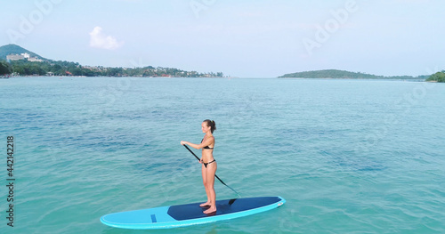 Aerial drone bird's eye view of man exercising sup paddle board in turquoise tropical clear waters, Thailand