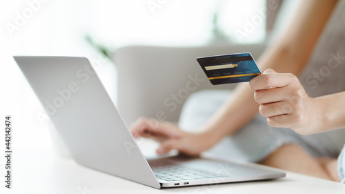 Young woman holding credit card and using laptop computer. Online shopping, internet banking, e-commerce, spending money, working from home concept