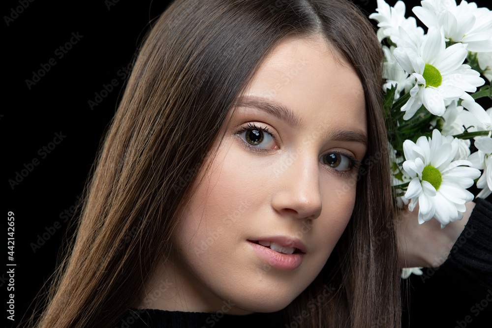 A beautiful young girl with natural beauty with long smooth hair holds a bouquet of white chrysanthemums. A beautiful young girl with natural beauty with long smooth hair holds a bouquet of white chrysanthemums.