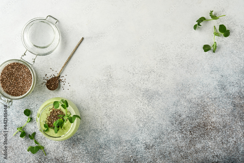 Ingredients for green smoothie, fresh organic spinach pea microgreens, banana, kiwi, apple and chia seed over light grey concrete background. Healthy eating ingredients. Top view, copy space Ingredients for green smoothie, fresh organic spinach pea microgreens, banana, kiwi, apple and chia seed over light grey concrete background. Healthy eating ingredients. Top view, copy space