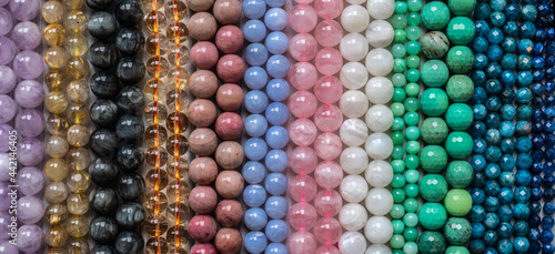 Beads from various types of natural stones are strung on a thread.