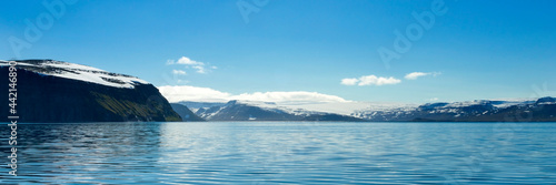 Beautiful mountains with snow picks and turquoise water of Atlantic ocean. Westfjords, Iceland. Horizontal banner. © Sonyara