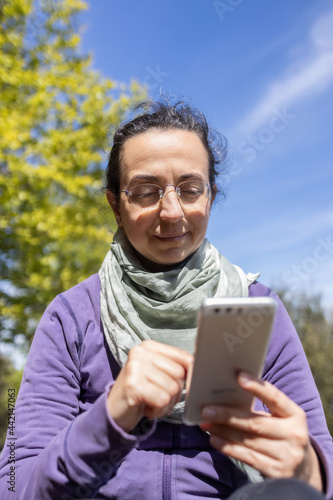 Pretty , young spanish woman in excursion in the forest, using mobile phone.