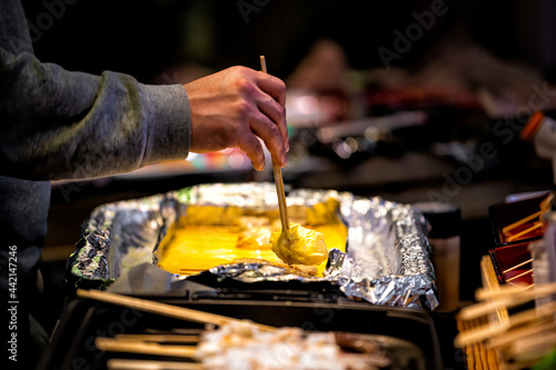 Closeup of tamagoyaki Japanese eggs rolled omelet on retail display in Kyoto  Japan Nishiki market street with person serving portion of omelette