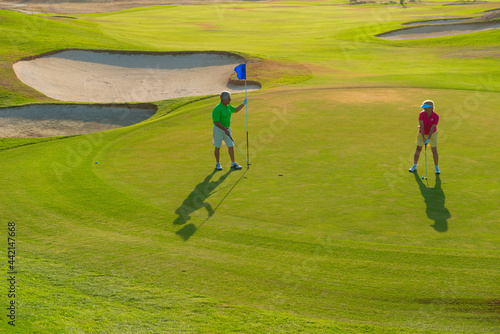 Active senior couple playing golf at sunset