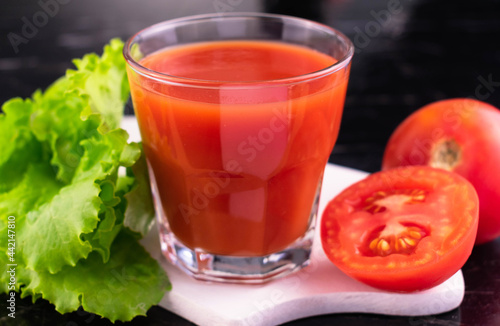 A glass of tomato juice on a black background. Close-up.