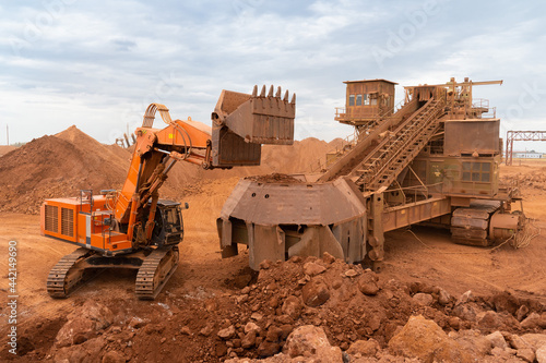 a large excavator loads rock into a crusher with a bucket