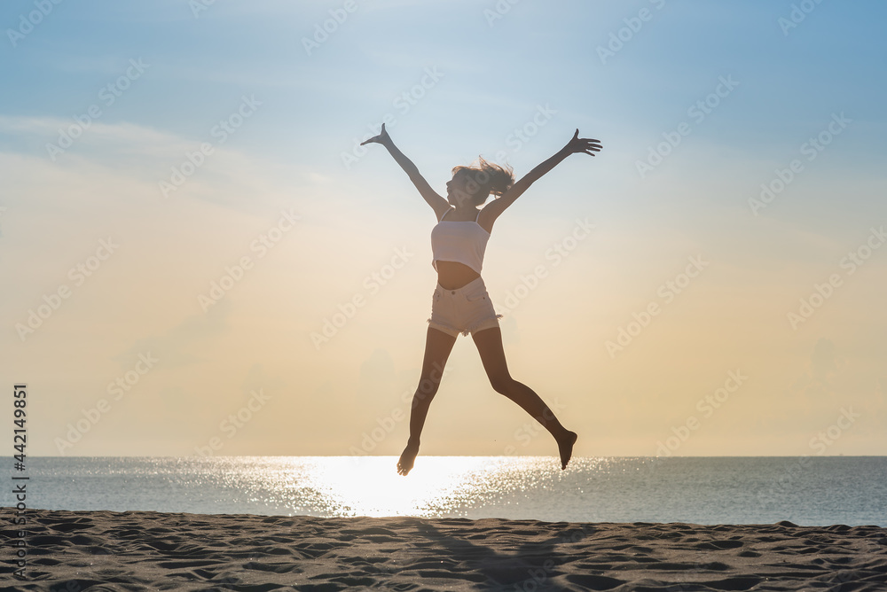 a young woman jumping on the beach.