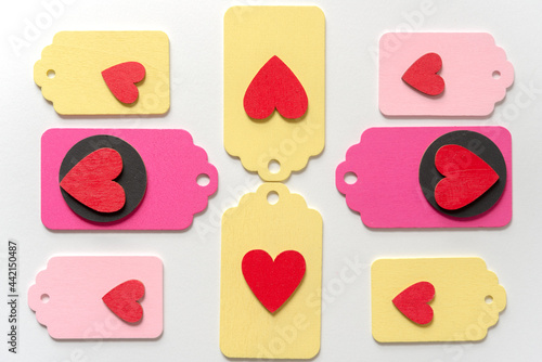 pastel colored wood chalkboard tags loosely arranged in a classic arragement with hand painted red hearts and black discs on a white paper background