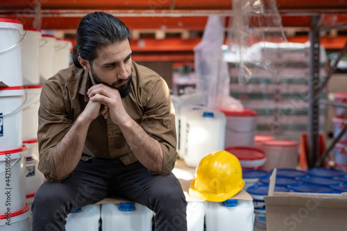 Tablou pe pânză Young tired male worker of warehouse having rest