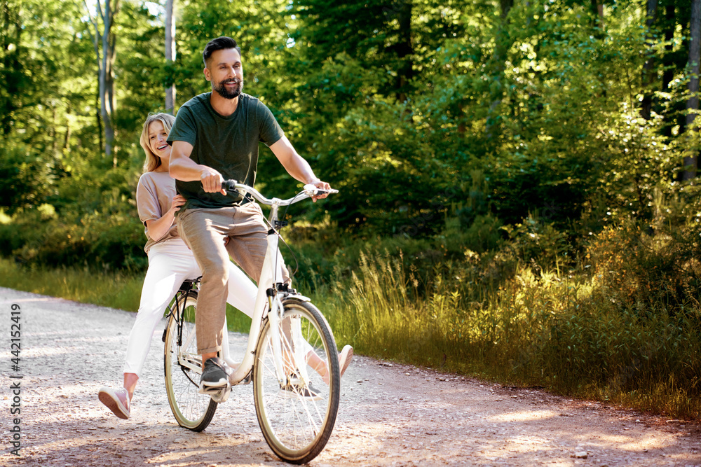 Obraz premium Playful couple having fun on a bike in the forest
